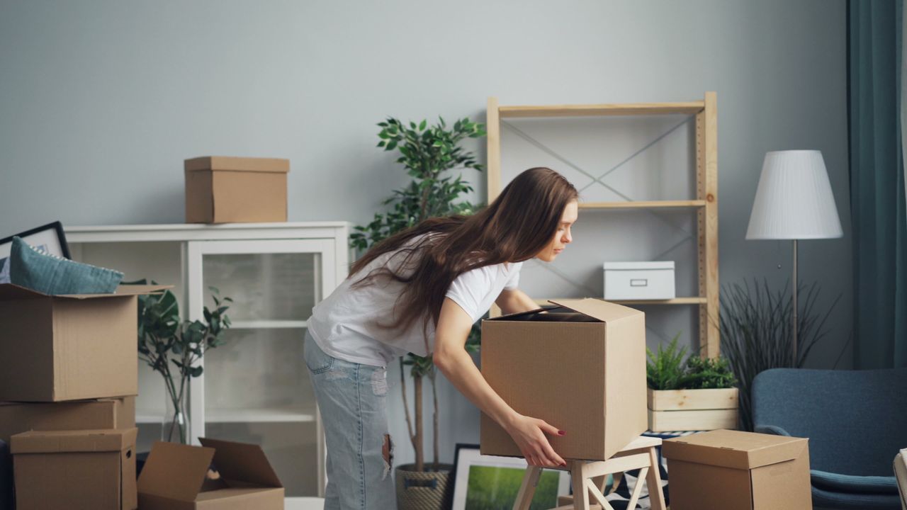 Services-01 A young woman with long hair arranging boxes in her new home. Ideal for moving and lifestyle stories.
